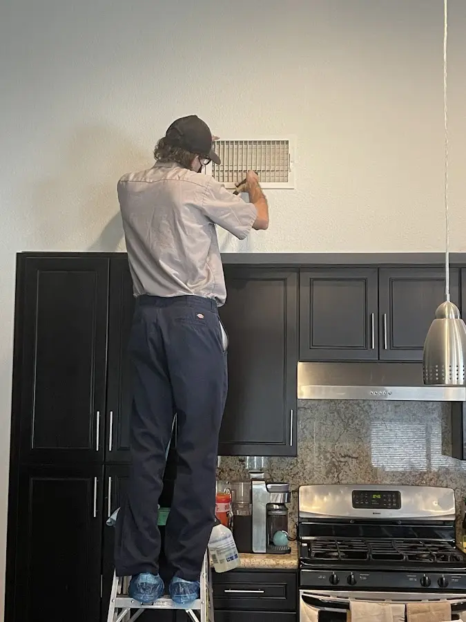 Technician inspecting an air vent during HVAC service in Waycross